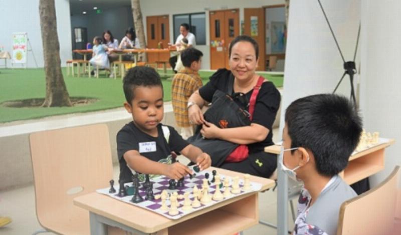 Một phụ huynh đang nhẹ nhàng chỉ tay, hướng dẫn con cách viết chữ hoặc đoạn văn trong sách bài tập tiếng Việt lớp 2 tập 2, thể hiện sự kiên nhẫn và tỉ mỉ